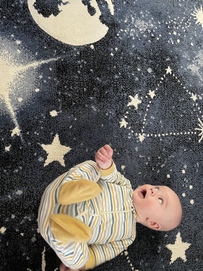 baby on their back on a starry and galaxy blanket