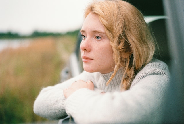 girl looking outside car window and pondering