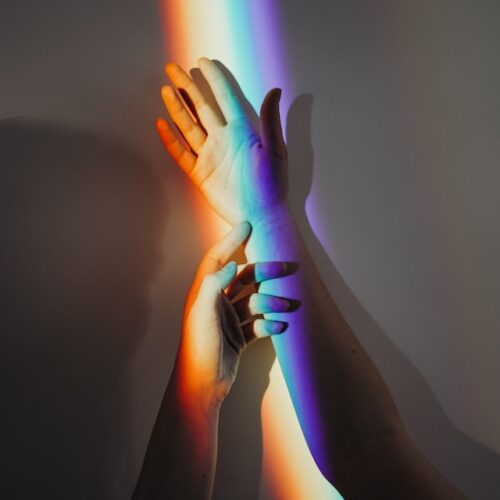 hands in front of a rainbow hands in front of a rainbow