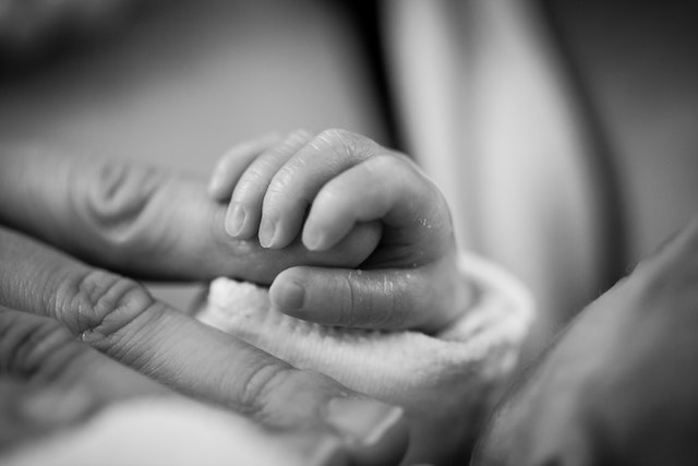 little baby finger grabbing mom's finger